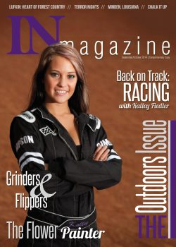 A woman in a racing suit stands with arms crossed on the cover of IN Magazine’s Outdoors Issue, September/October 2014.