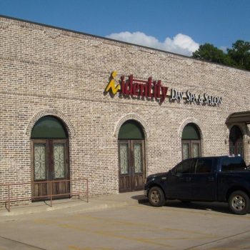 A brick building with arched windows houses Identity Day Spa & Salon; a black pickup truck is parked in front.