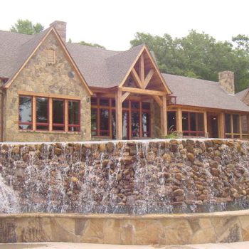 Stone house with large windows and gabled roof, featuring a rock waterfall cascading down the front.