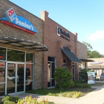 Domino’s Pizza storefront next to Rockwell’s Coffee Bar in a small brick shopping center on a sunny day.