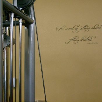 A Life Fitness gym machine beside a wall with a Mark Twain quote about getting started to get ahead.