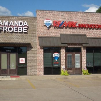 Storefronts for Amanda Froebe State Farm Insurance and RE/MAX Innovation in a brick strip mall, seen from a parking lot.