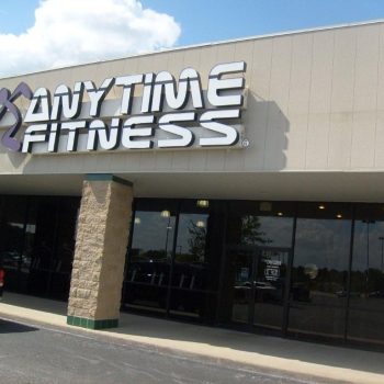 Exterior view of an Anytime Fitness gym with large signage above the entrance on a sunny day.