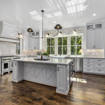Modern kitchen with white cabinetry, a large island, stainless steel appliances, and hardwood floors.