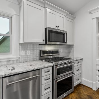 Modern kitchen with white cabinets, stainless steel appliances, marble countertop, and subway tile backsplash.