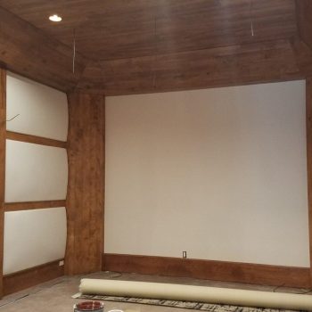 A room with wood paneling and white acoustic panels on the walls, under construction with materials on the floor.