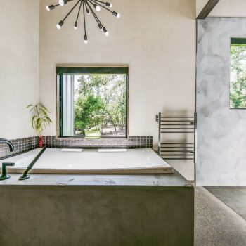 Modern bathroom with a built-in bathtub, large window, towel warmer, and walk-in shower with hexagonal tiles.