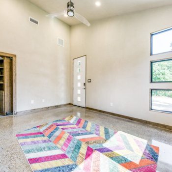 Bright, empty room with polished floor, colorful rug, square windows, ceiling fan, and an open closet door.