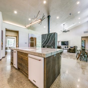 Modern open-concept kitchen and living area with marble island, dining table, and large windows.