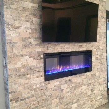 Television mounted above an electric fireplace with blue flames on a stone accent wall.