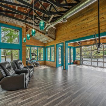Modern room with wood walls, large windows, two recliners, exercise equipment, and river views.