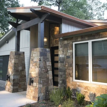 Modern house exterior with stone pillars, large windows, wood accents, and a black garage door under a sloped roof.