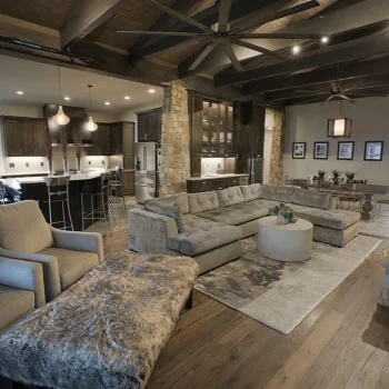 Modern open-concept living room and kitchen with exposed beams, stone accents, and contemporary furnishings.
