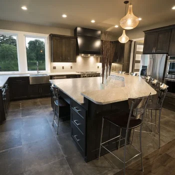 Modern kitchen with dark cabinets, a large island with stools, stainless steel appliances, and pendant lighting.