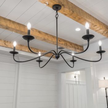 A black metal chandelier with six exposed bulbs hangs from a white ceiling with wooden beams in a modern room.