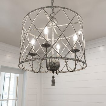 A metal cage chandelier with four candle-style lights hangs from a ceiling in a room with white shiplap walls.
