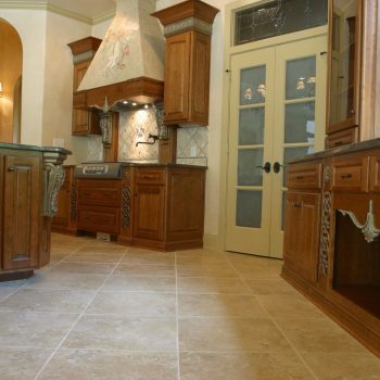Spacious kitchen with wood cabinets, granite countertops, tile floor, and double glass doors.