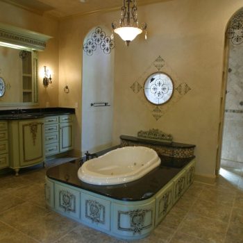 Luxurious bathroom with ornate green cabinetry, a central bathtub, and a walk-in shower with tiled walls.