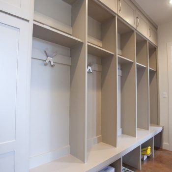 Built-in mudroom cubbies with open storage, hooks, upper cabinets, and bench seating along the wall.