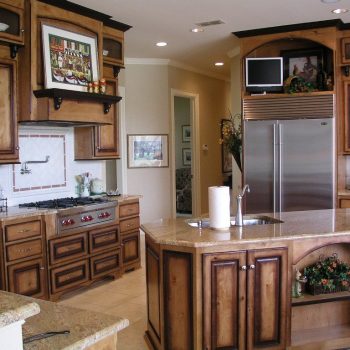 Spacious kitchen with wooden cabinets, granite countertops, stainless steel fridge, and a central island with a sink.