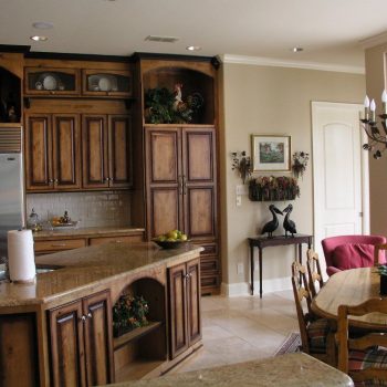 Kitchen with wooden cabinets, granite countertops, a dining table with chairs, and decorative items throughout the space.