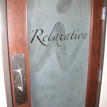Frosted glass door with the word "Relaxation" and a stylized figure etched on it; wood frame and metal handle.