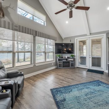 Living room with wood floors, recliner, TV, rug, large windows, and French doors leading outside.